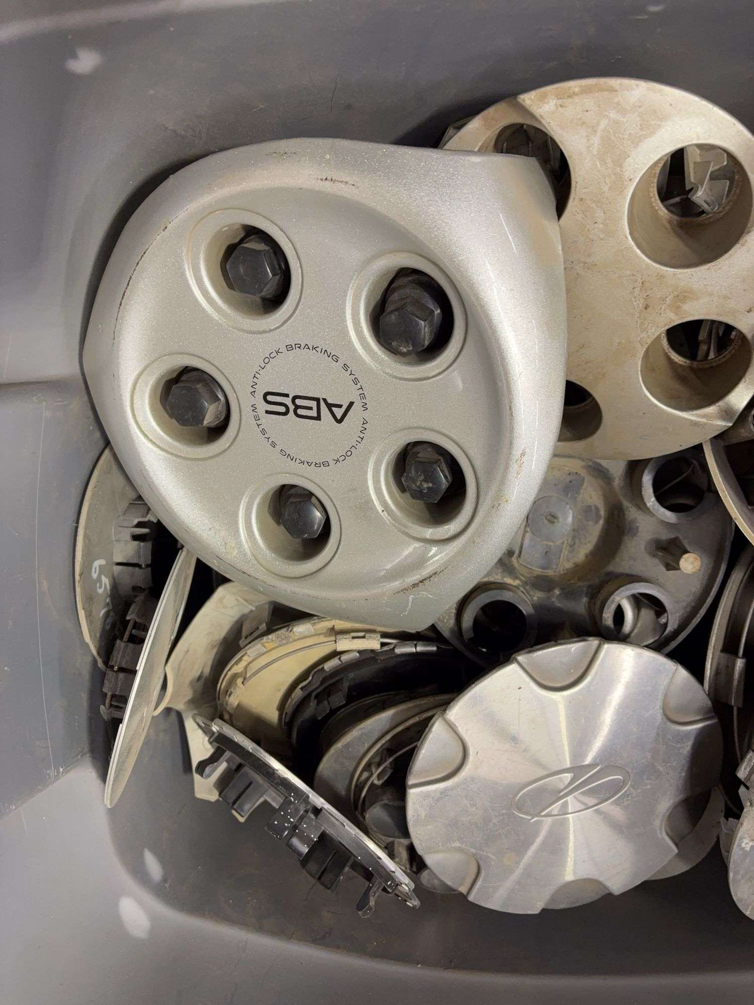 Tote of miscellaneous hub caps and parts -including Ford, Chevy and more - see photos