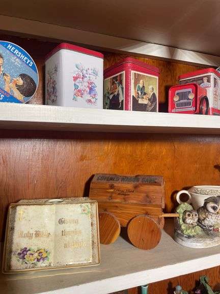 Contents of 2 shelves - including tins, decorative glassware, wooden wagon & more