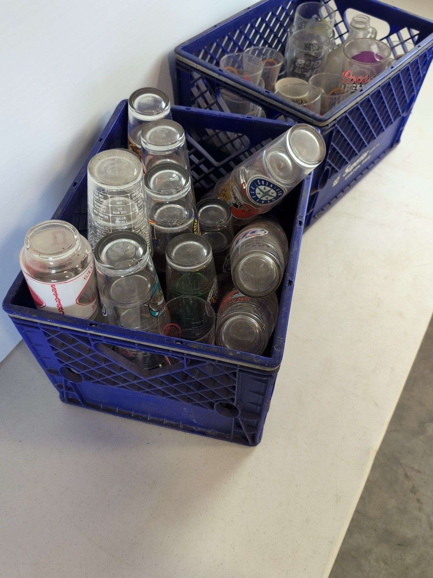 Bar glasses with sports logos in (2) milk crates