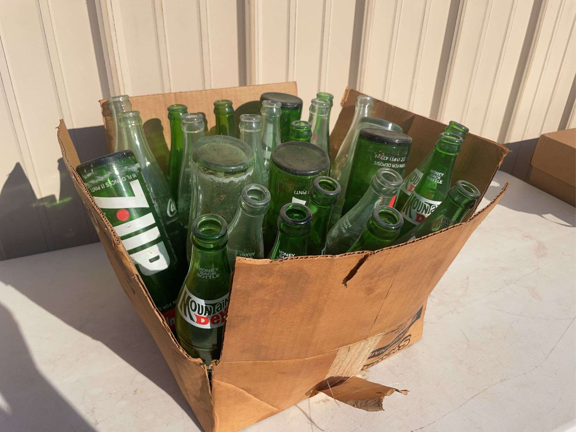 Box of empty 7-up and Mountain Dew bottles