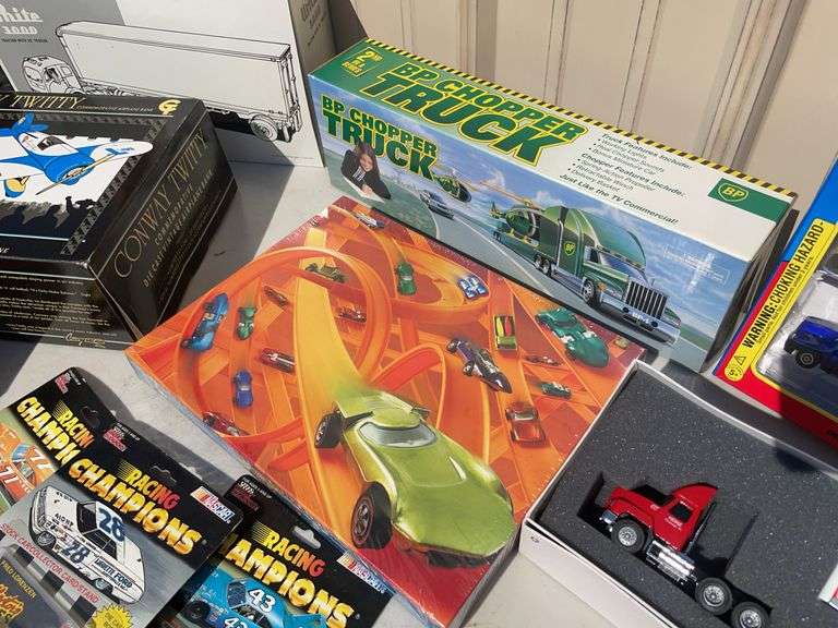 Box of mostly new cars/ toys including hot rod hauler, racing Champions car, BP Chopper Truck and mo