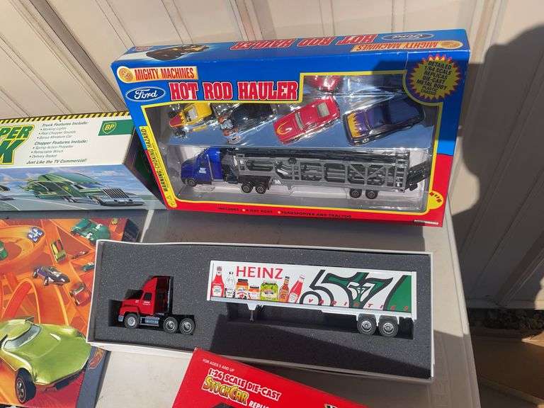 Box of mostly new cars/ toys including hot rod hauler, racing Champions car, BP Chopper Truck and mo